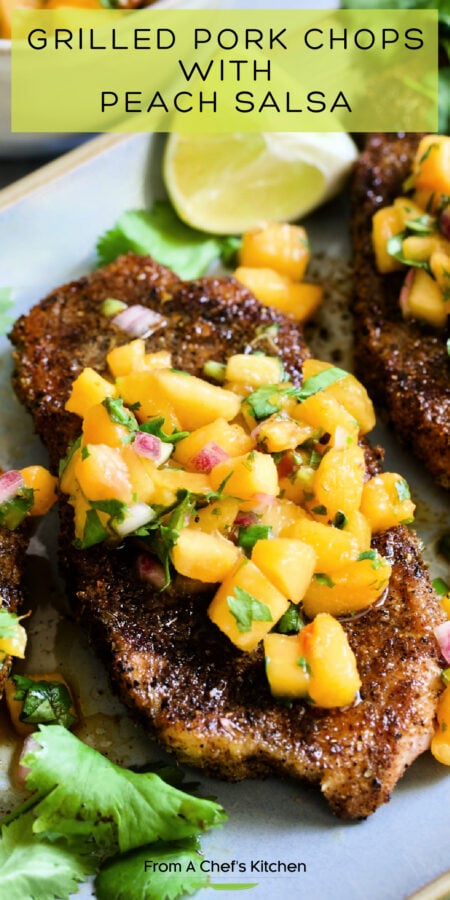 Pinterest graphic for Grilled Pork Chops with Peach Salsa showing them on a gray oval platter garnished with lime wedges and fresh cilantro.