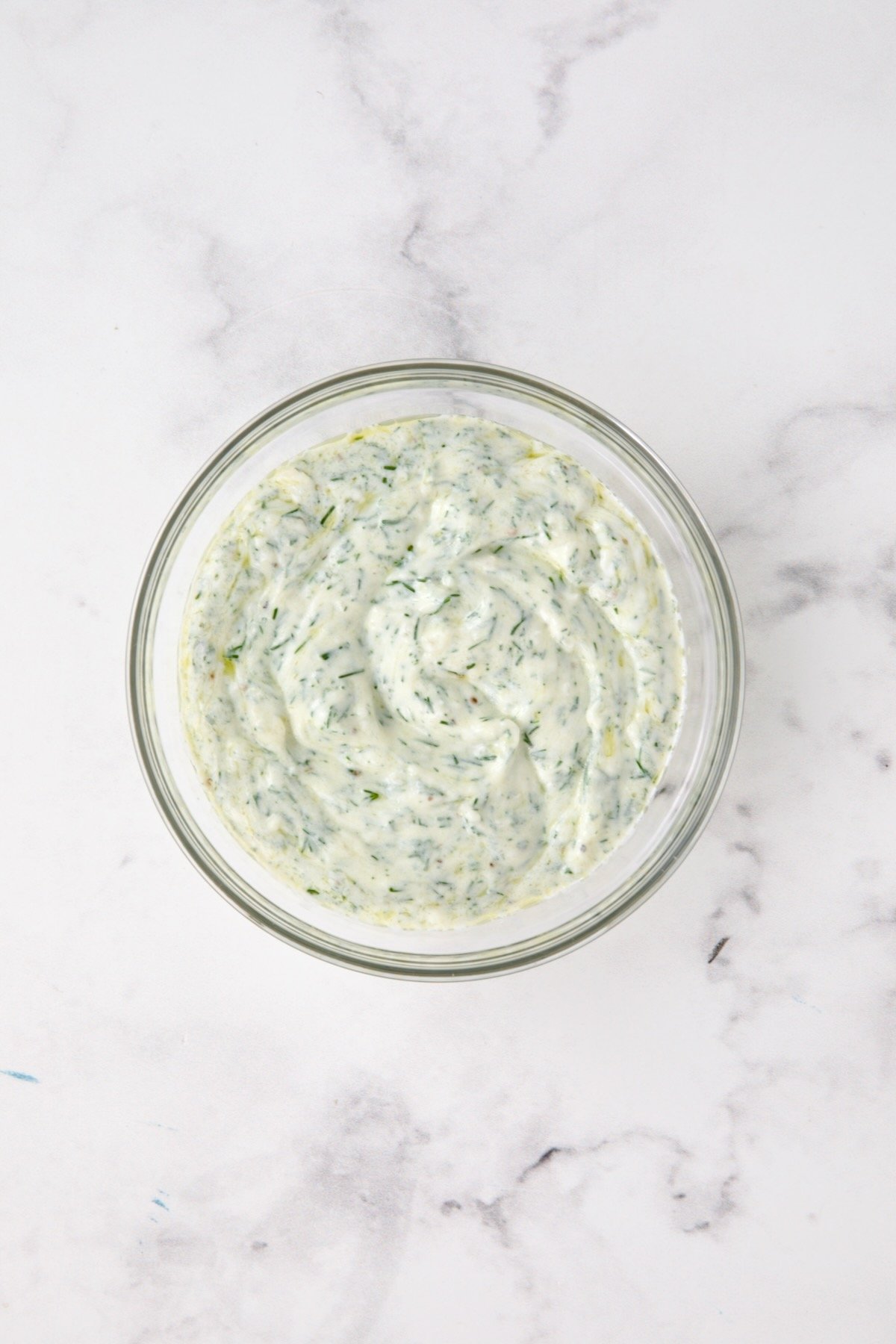 Dill yogurt in glass bowl.