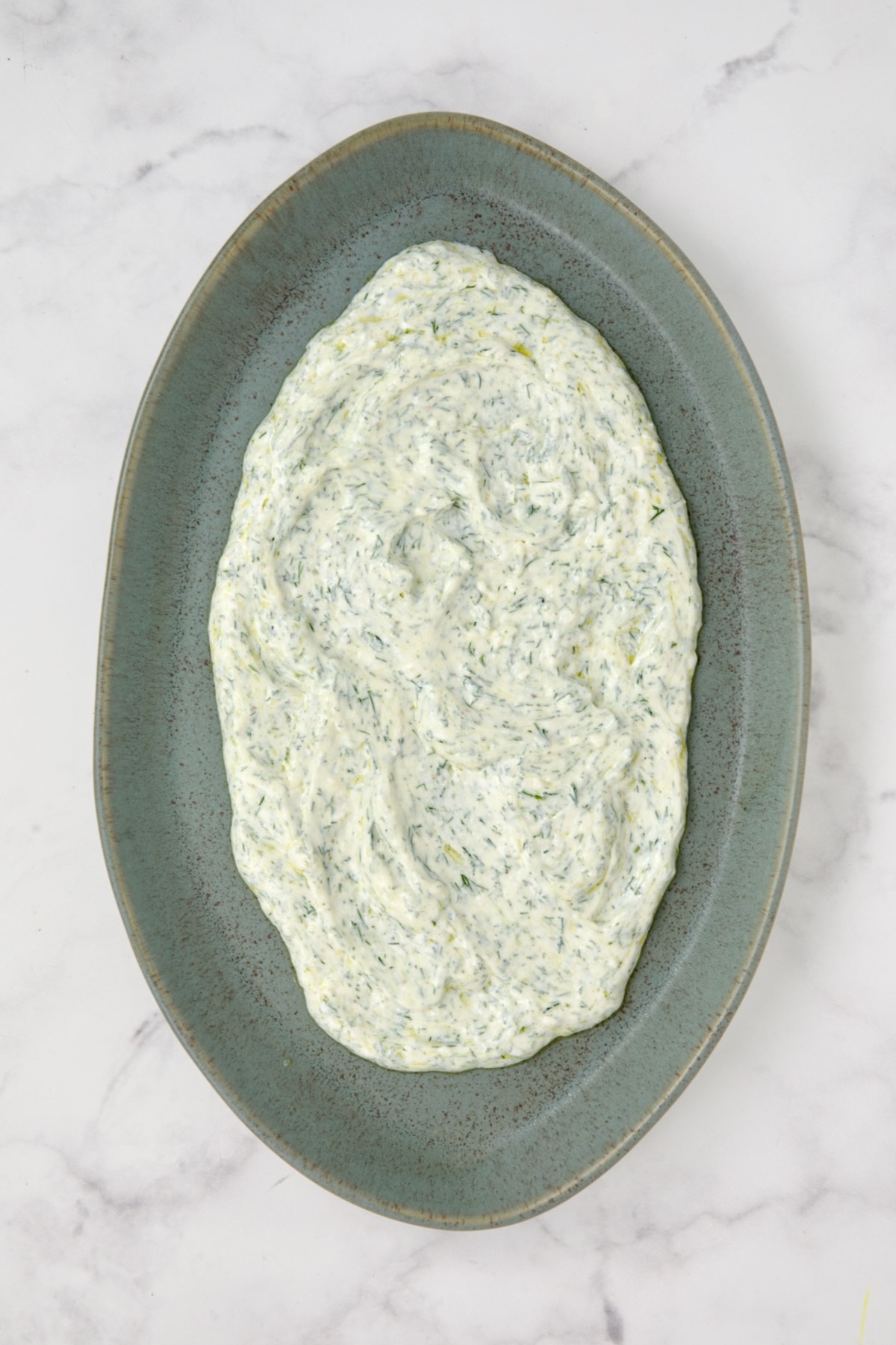 Dill yogurt spread out on blue platter.