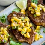 Three Pork Chops with Peach Salsa on oval gray platter.