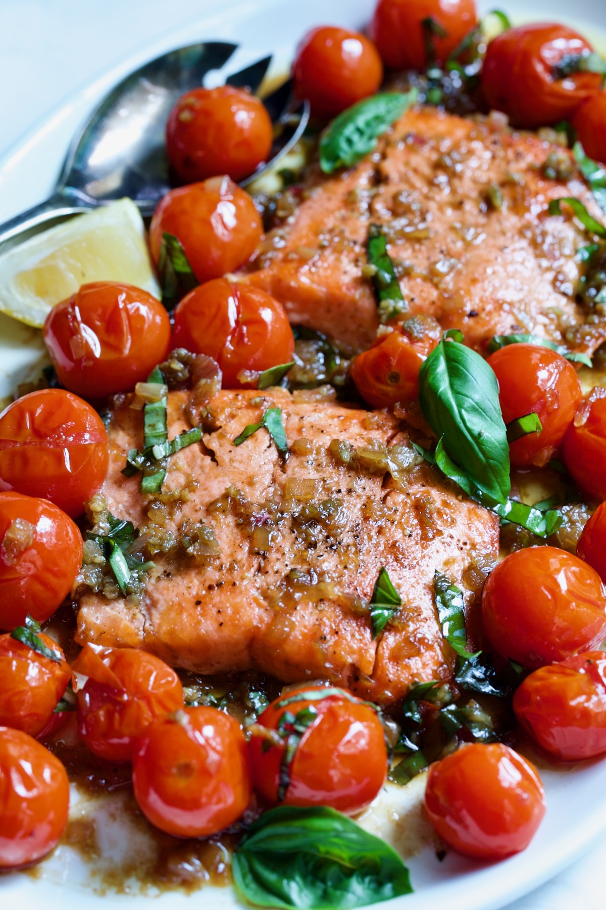 Salmon with Balsamic Cherry Tomatoes on oval white platter with serving fork.