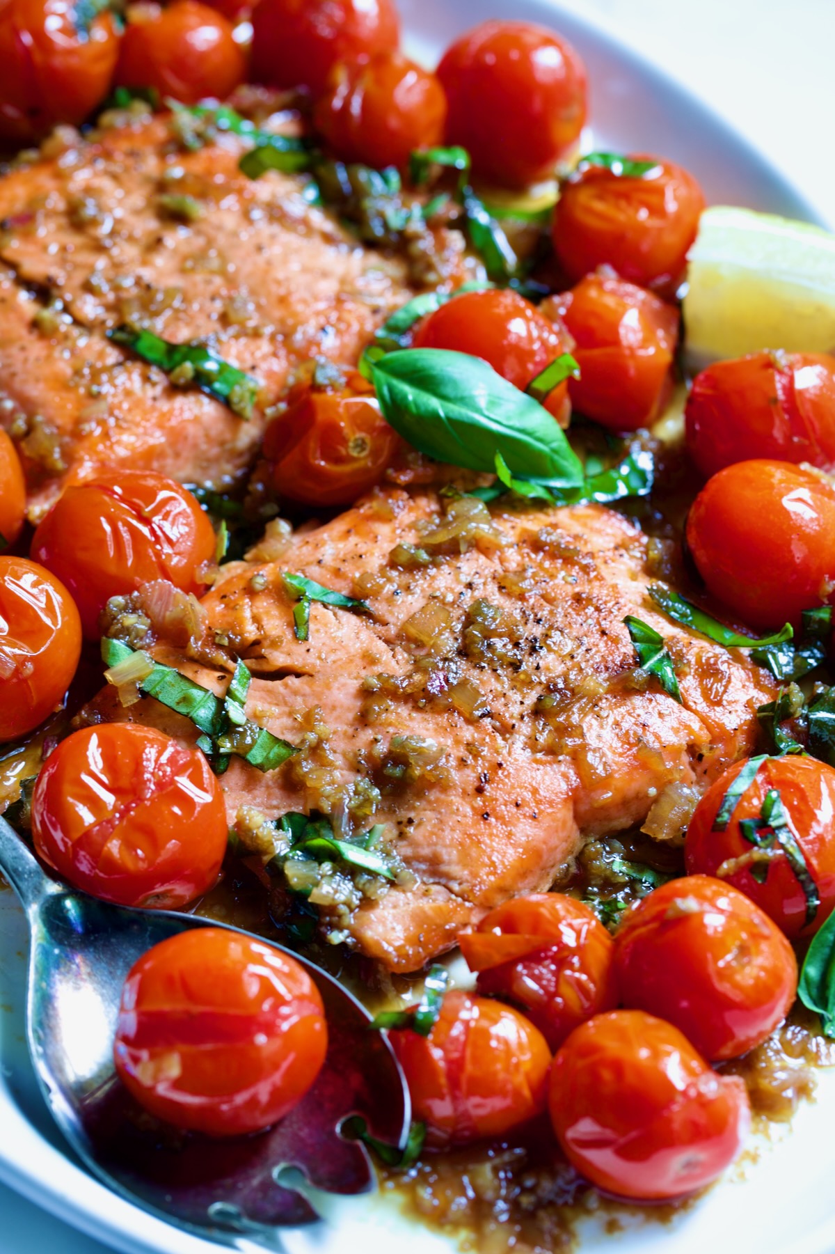 Salmon with Balsamic Cherry Tomatoes on oval white platter with serving fork.