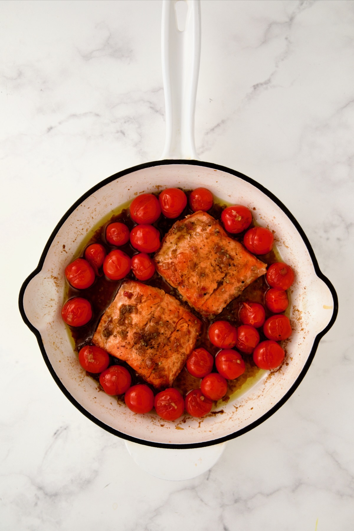 Salmon added to the balsamic cherry tomatoes in white enamel cast iron skillet.