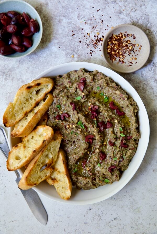 Eggplant Caviar (Caviar d'Aubergine) in white bowl with five pieces of grilled bread on the side.
