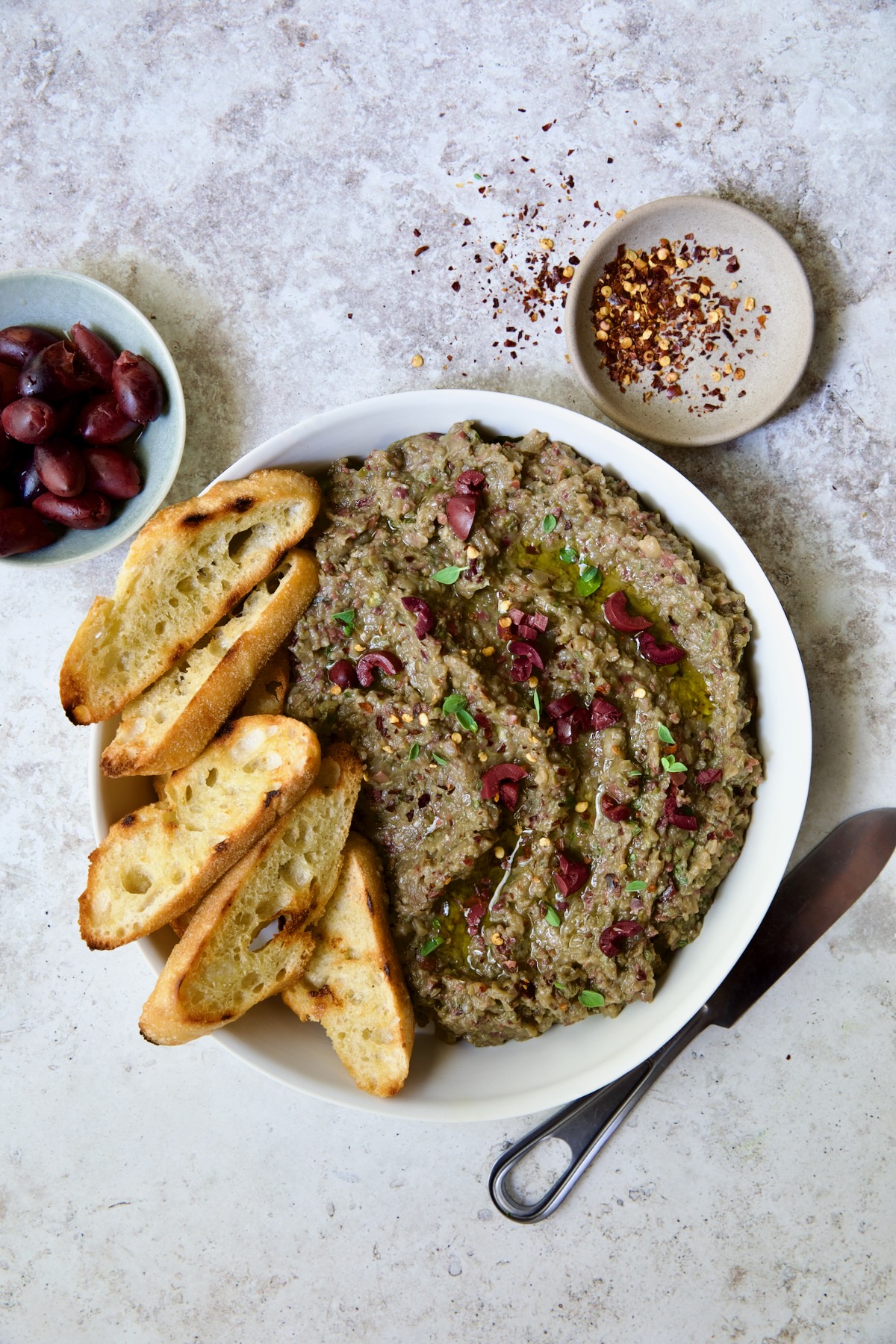 Eggplant Caviar (Caviar d'Aubergine) in white bowl with five pieces of grilled bread on the side.