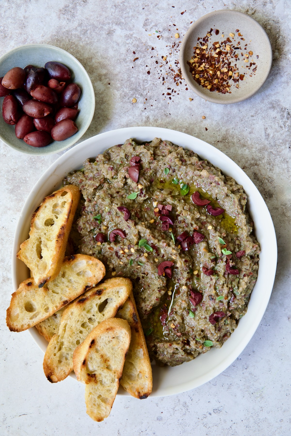 Eggplant Caviar (Caviar d'Aubergine) in white bowl with five pieces of grilled bread on the side.