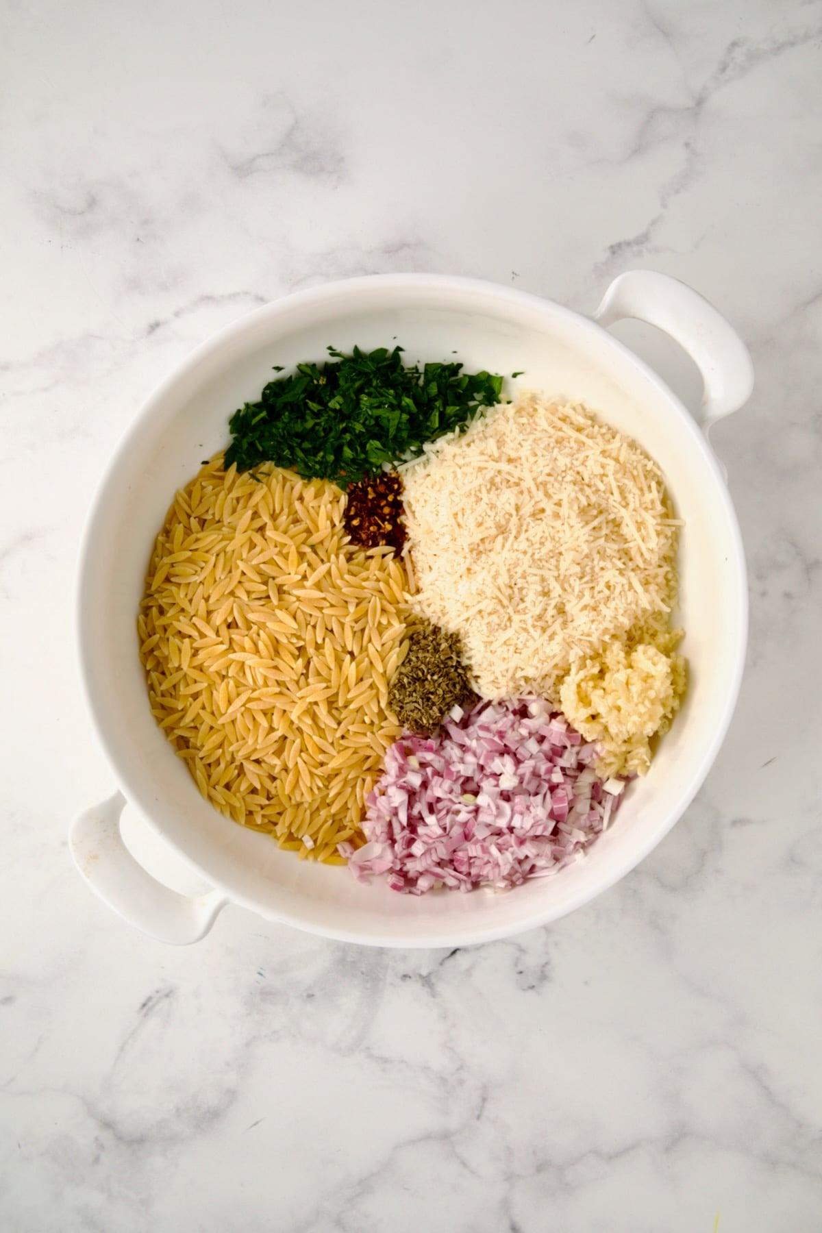 Ingredients for tian in round white baking dish before being mixed together.