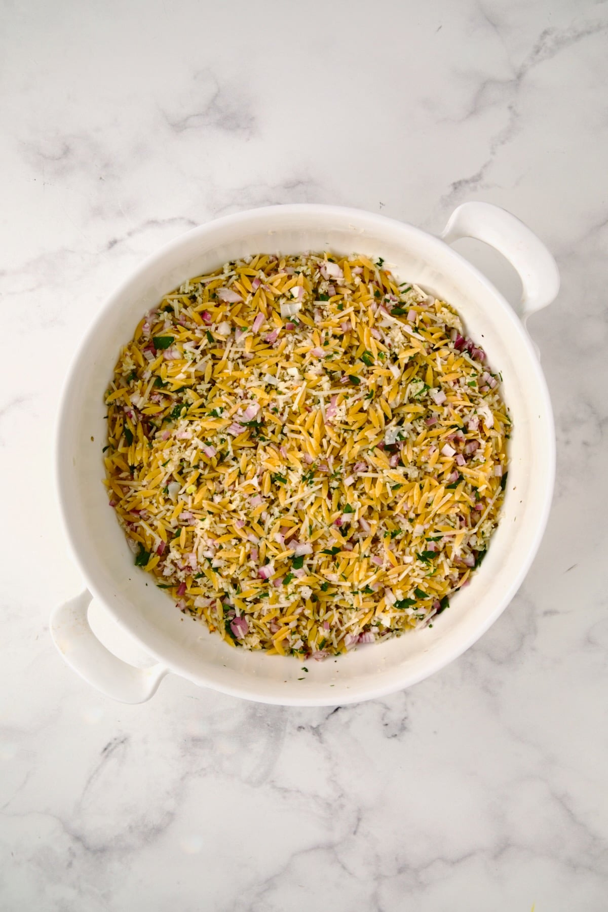 Ingredients for tian in round white baking dish after being mixed together.