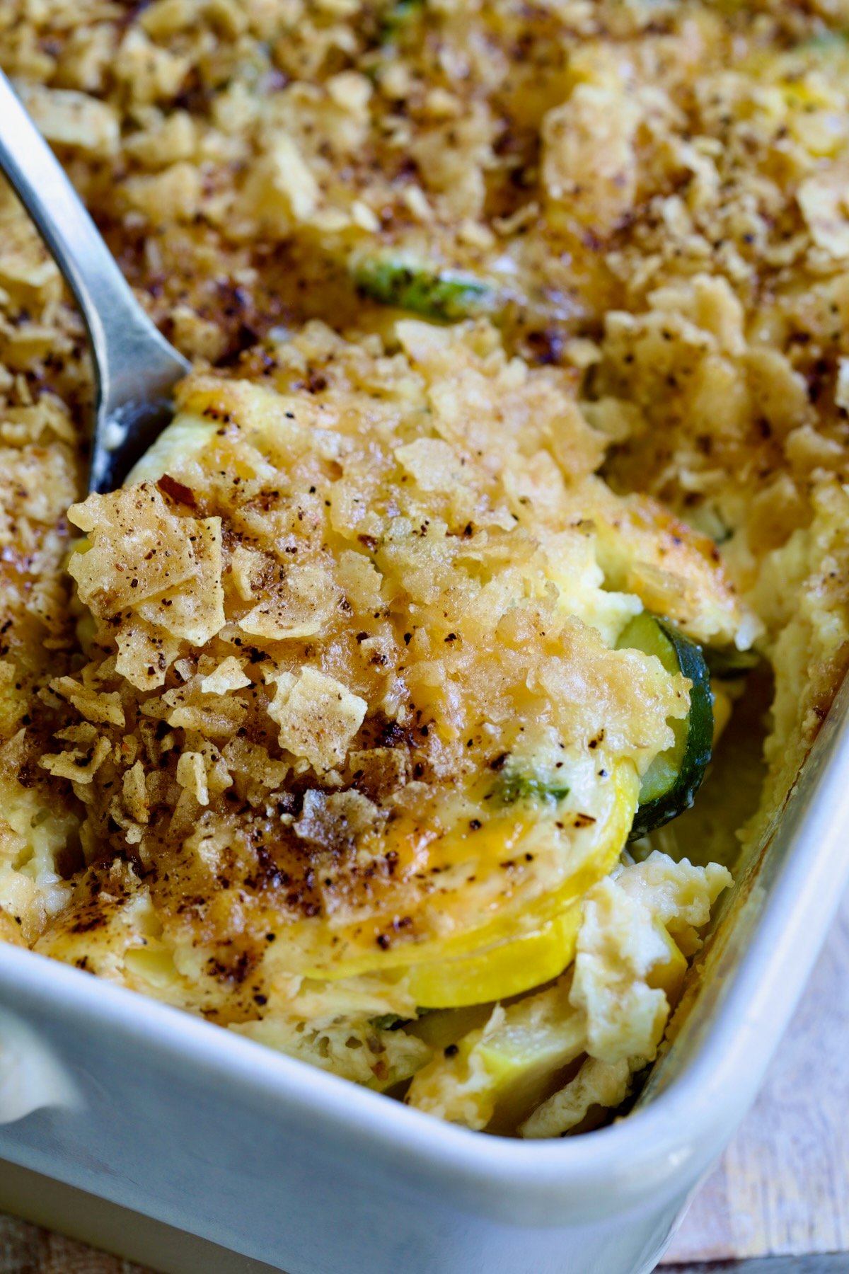 Summer Squash Corn Poblano Casserole in rectangular white baking dish with serving spoon.
