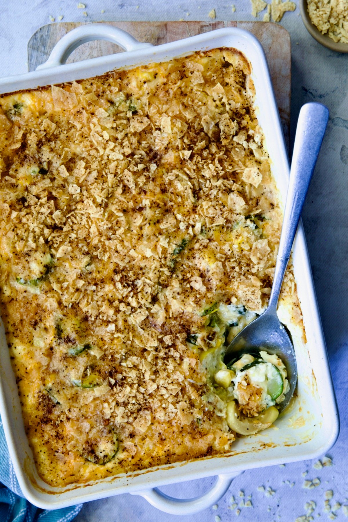 Summer Squash Corn Poblano Casserole in rectangular white baking dish with serving spoon.