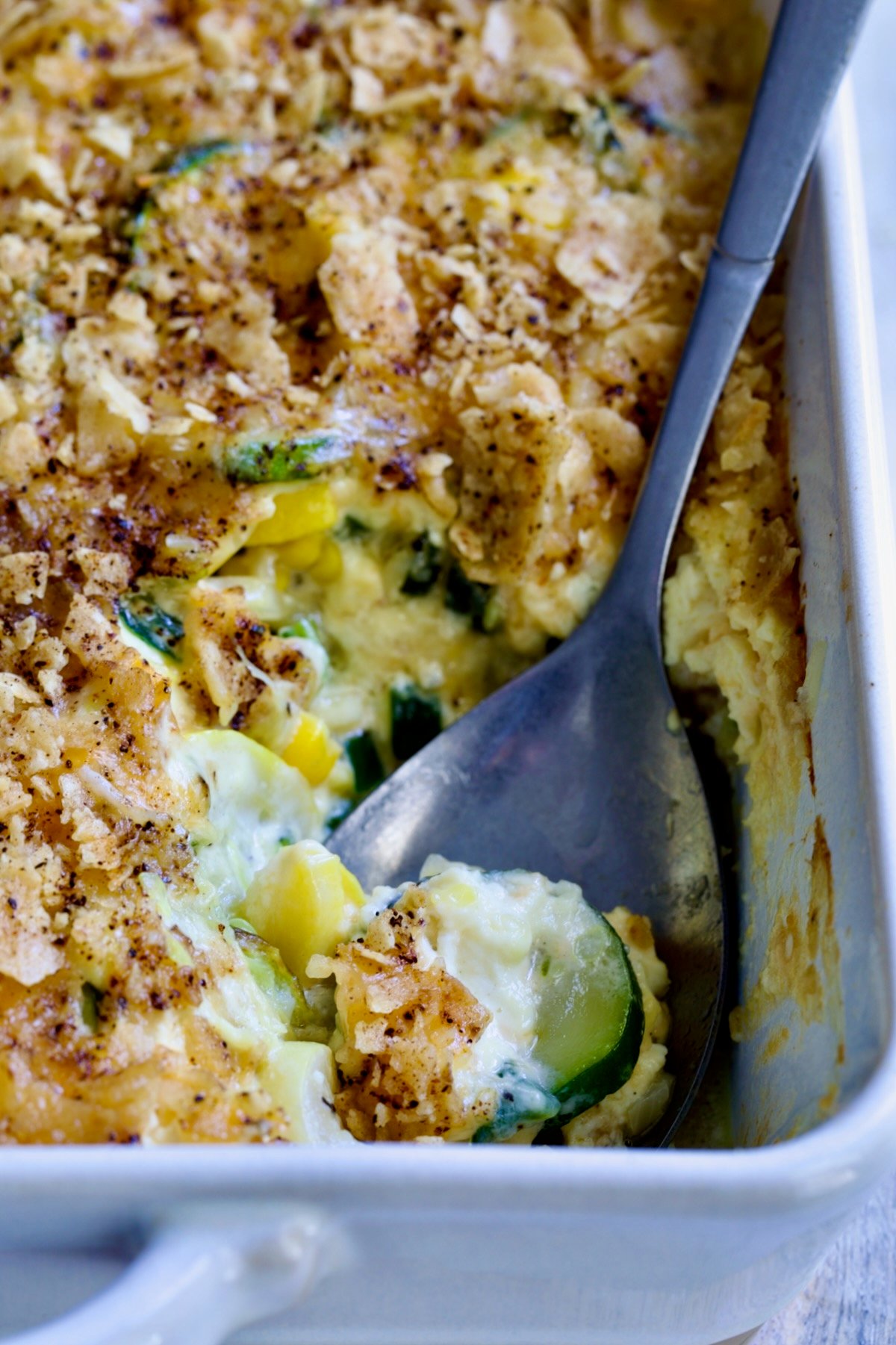Summer Squash Corn Poblano Casserole in rectangular white baking dish with serving spoon.