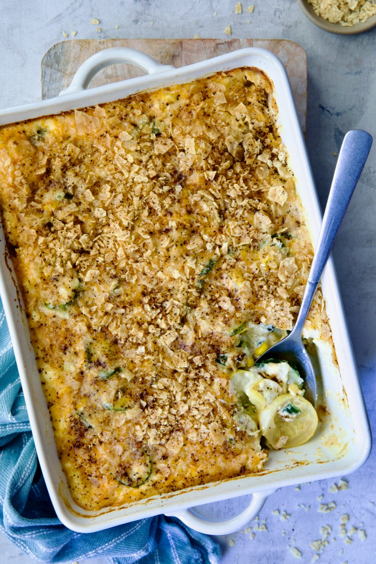 Summer Squash Corn Poblano Casserole in rectangular white baking dish with serving spoon.