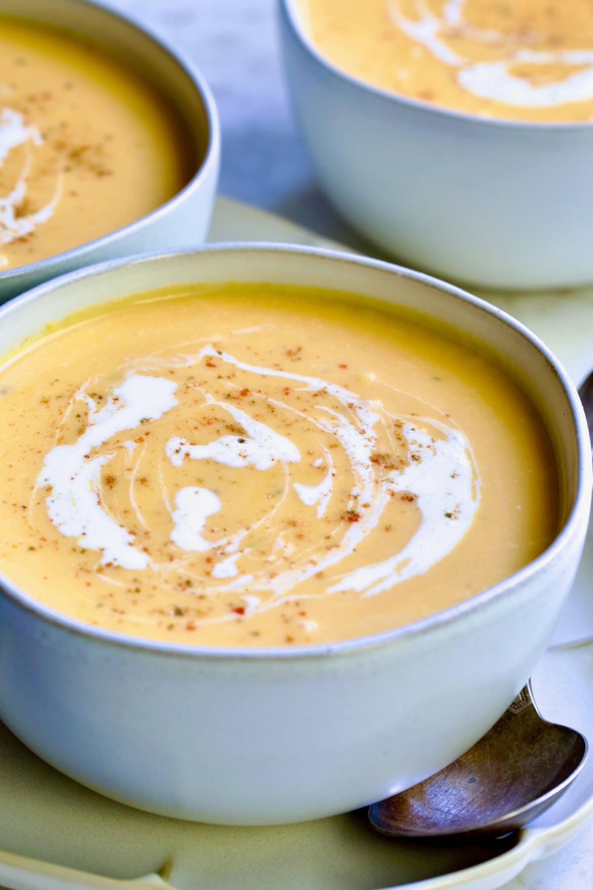 One serving of Butternut Squash Brie Soup in white bowl.