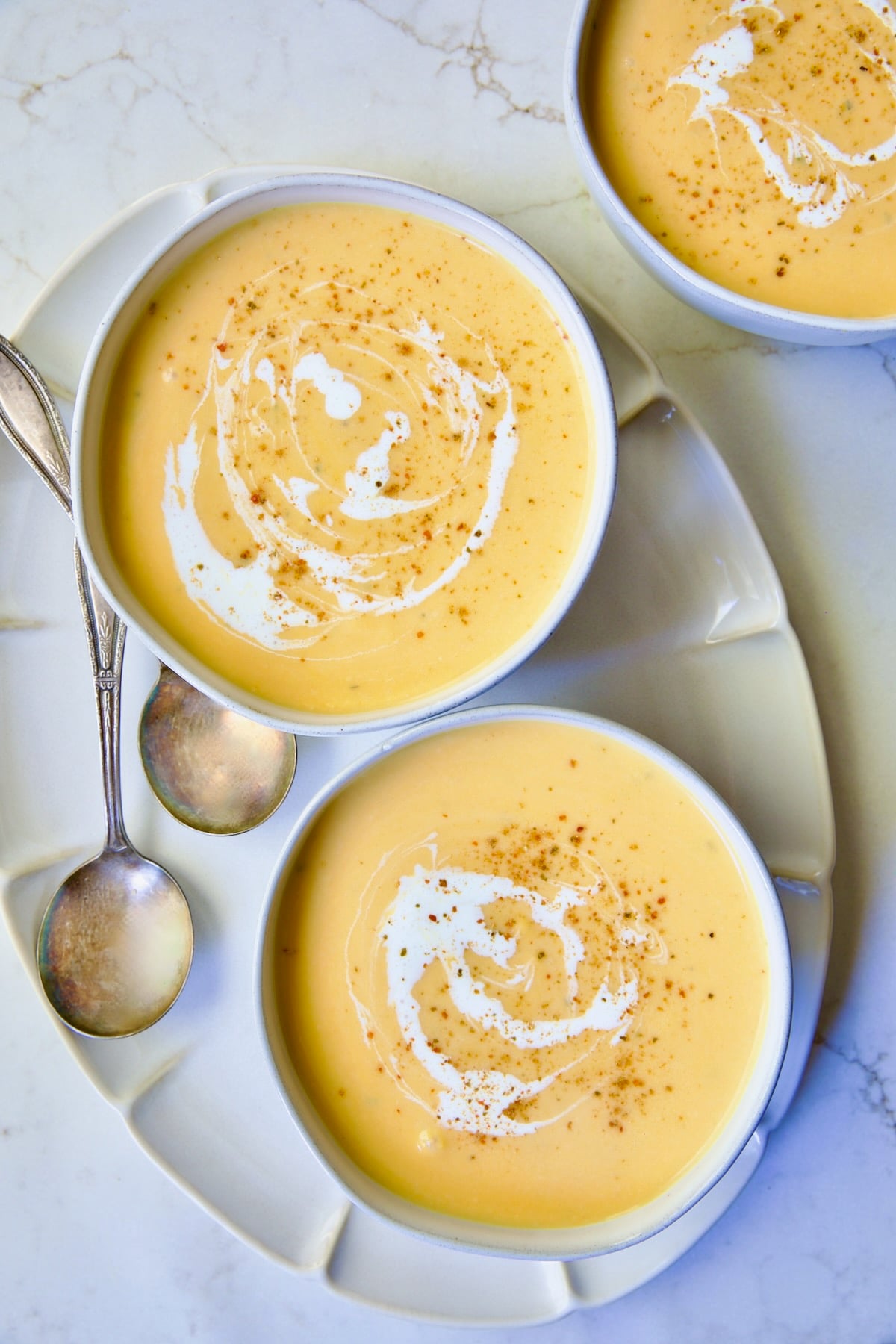 Three servings of Butternut Squash Brie Soup in white bowls.