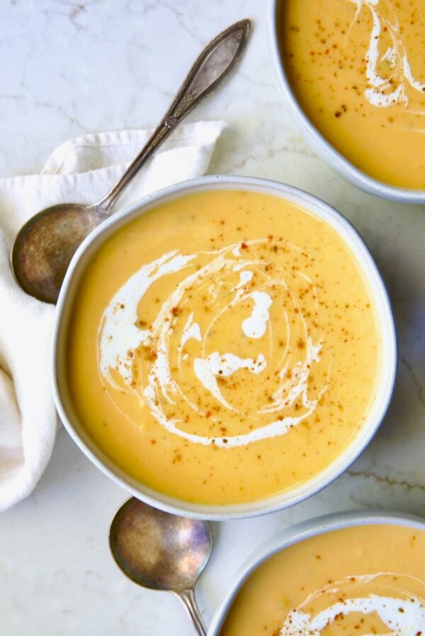 Three servings of Butternut Squash Brie Soup in white bowls.