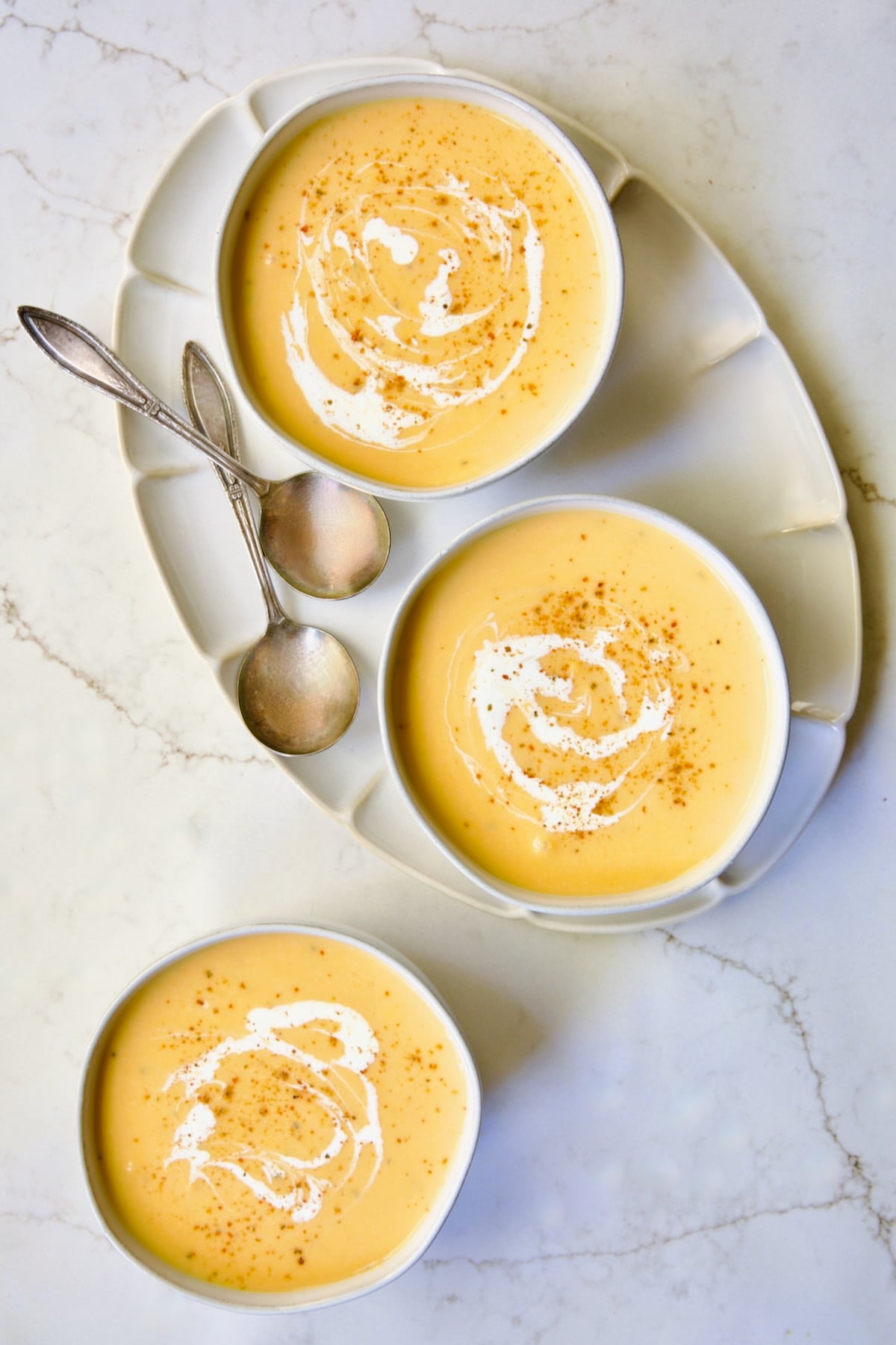 Three servings of Butternut Squash Brie Soup in white bowls.