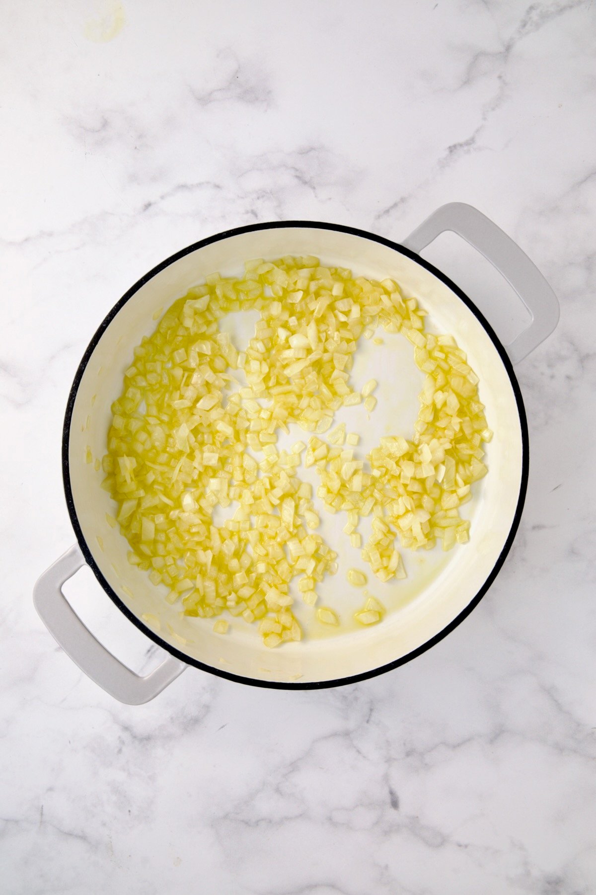 Cooked onions in white enamel cast iron skillet.