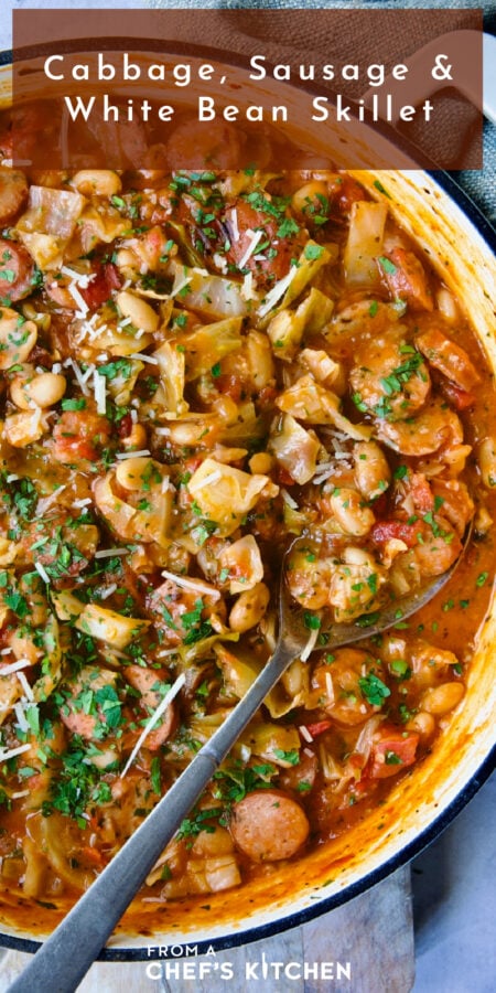 Pinterest graphic for Cabbage, Sausage and White Bean Skillet showing it in a white enamel cast iron skillet with serving spoon.