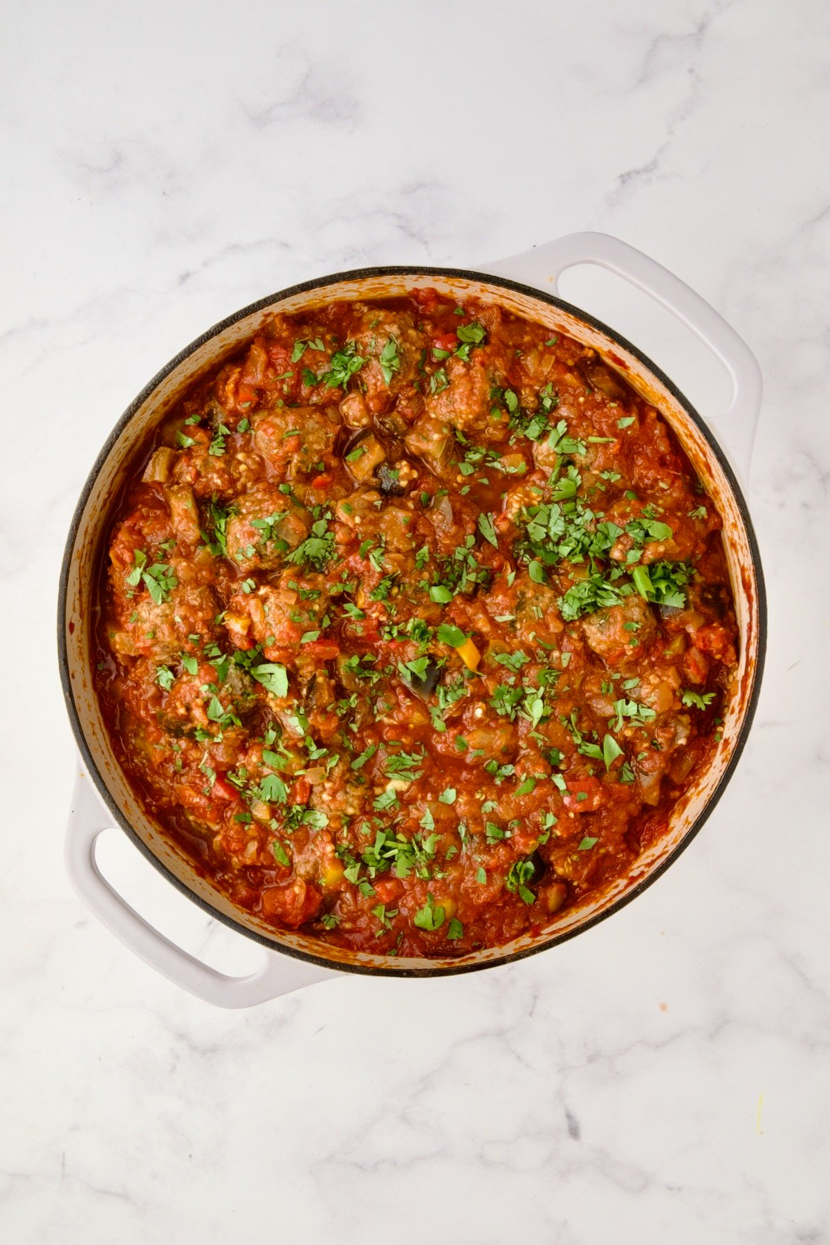 Moroccan Meatball Stew in white enamel cast iron skillet.