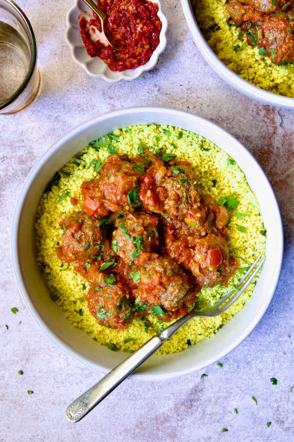One serving of Moroccan Meatball Stew in earthenware bowl over couscous.