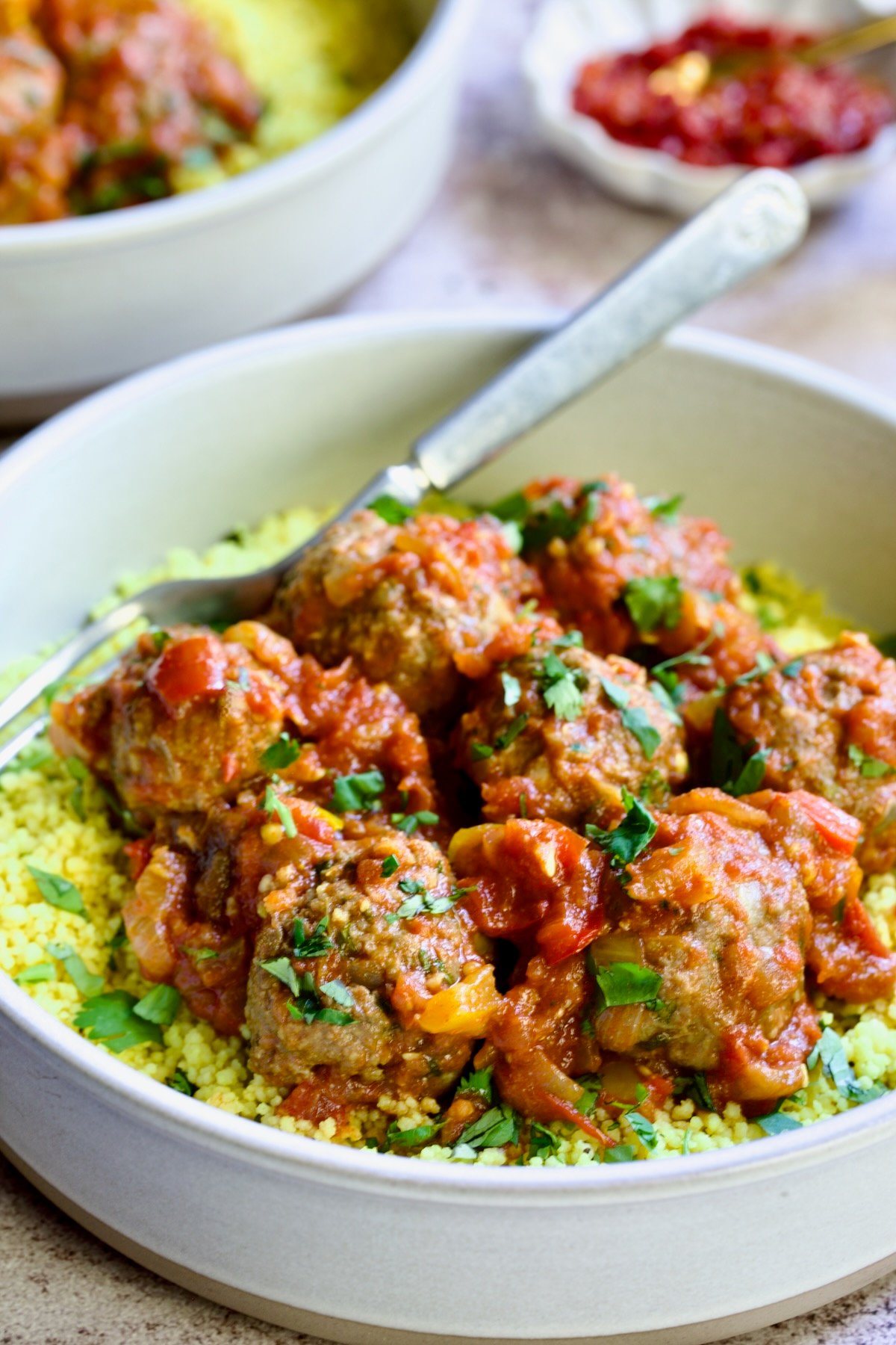 One serving of Moroccan Meatball Stew in earthenware bowl over couscous.