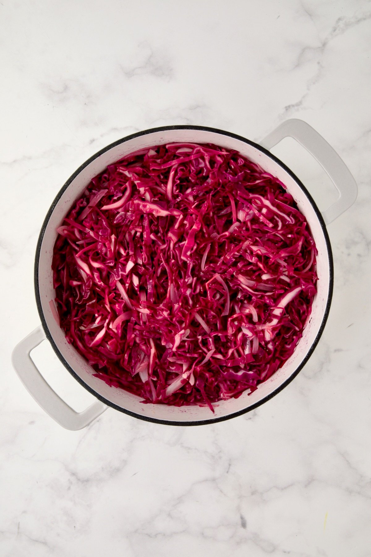 Wilted red cabbage in white enamel cast iron skillet.