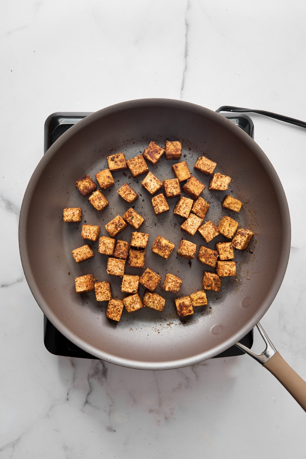 Cubed, seasoned tofu cubes in nonstick skillet.