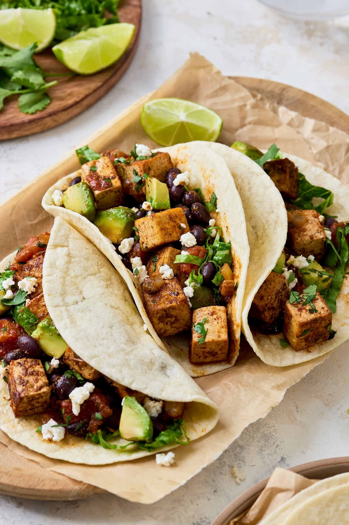 Three Tofu Black Bean Tacos on parchment paper lined wooden tray.