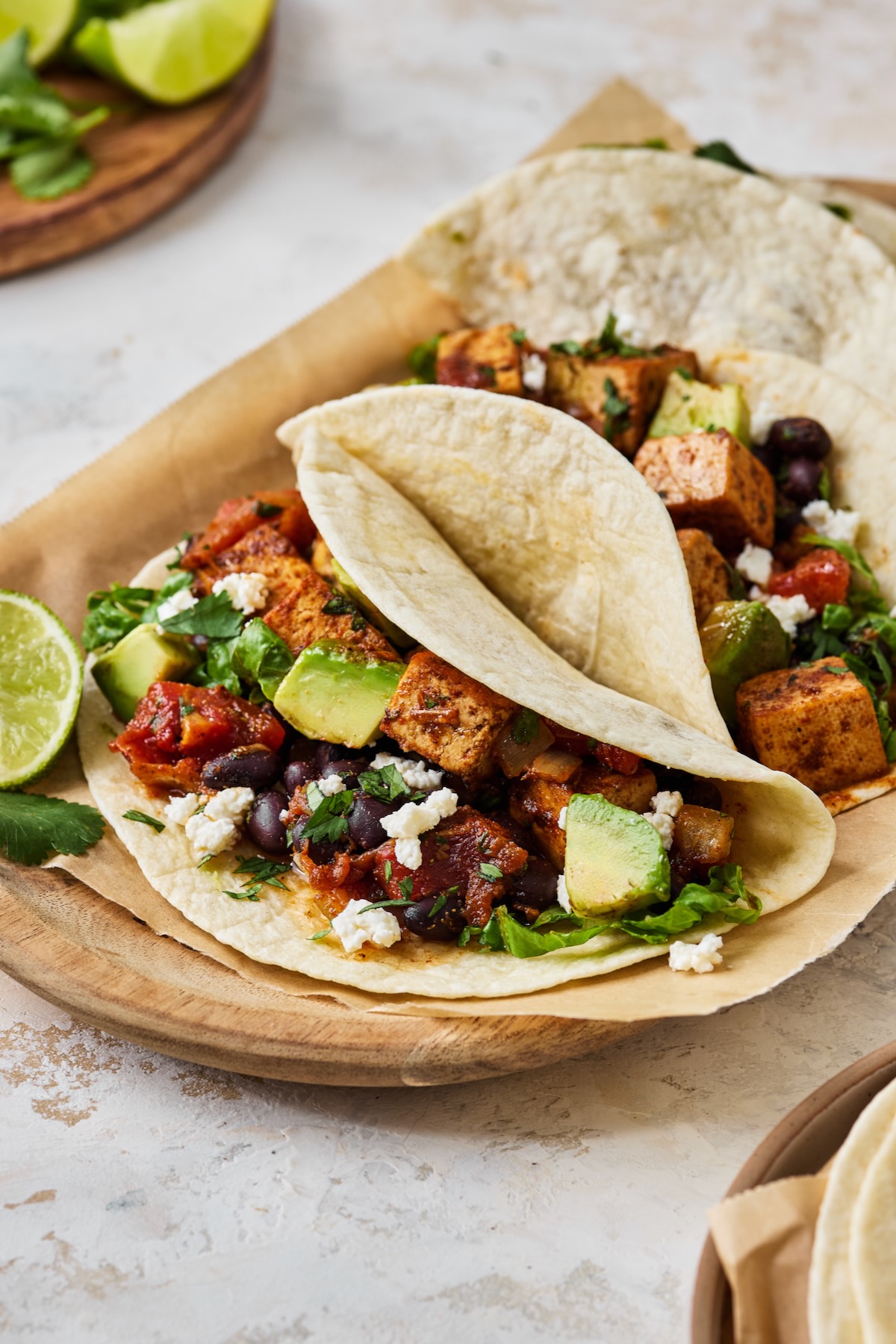 Close-up of Tofu Black Bean Taco on parchment paper lined wooden tray.