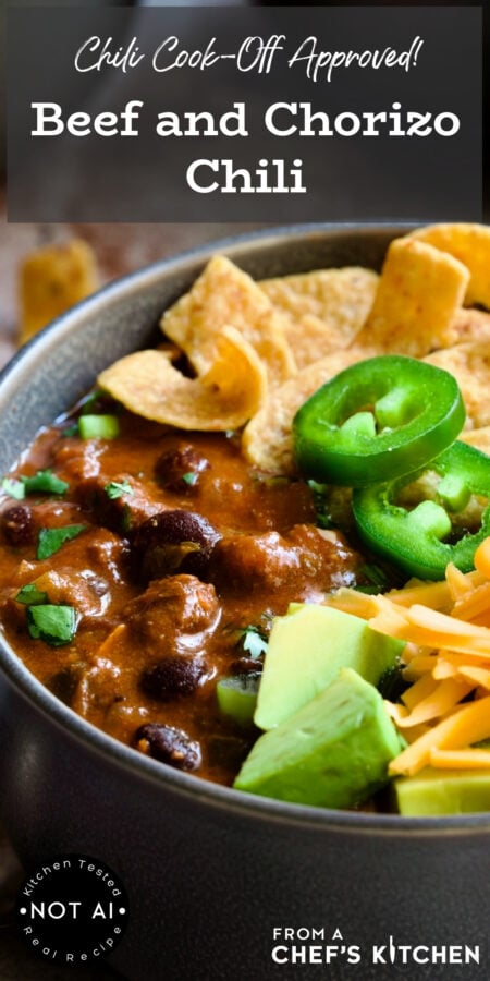 Pinterest graphic for Beef and Chorizo Chili showing one serving in a gray bowl garnished with avocado, cheddar, jalapeno, corn chips and sour cream.