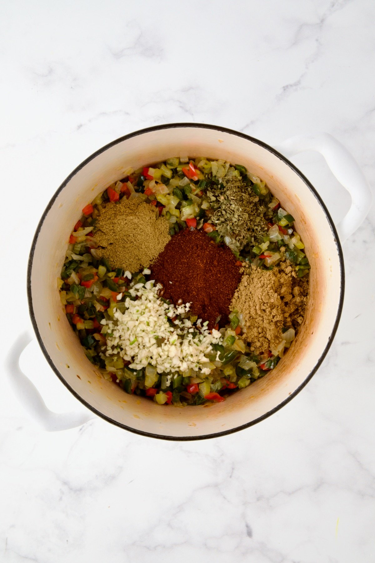 Spices added to cooked onions, celery and peppers in white enamel Dutch oven.
