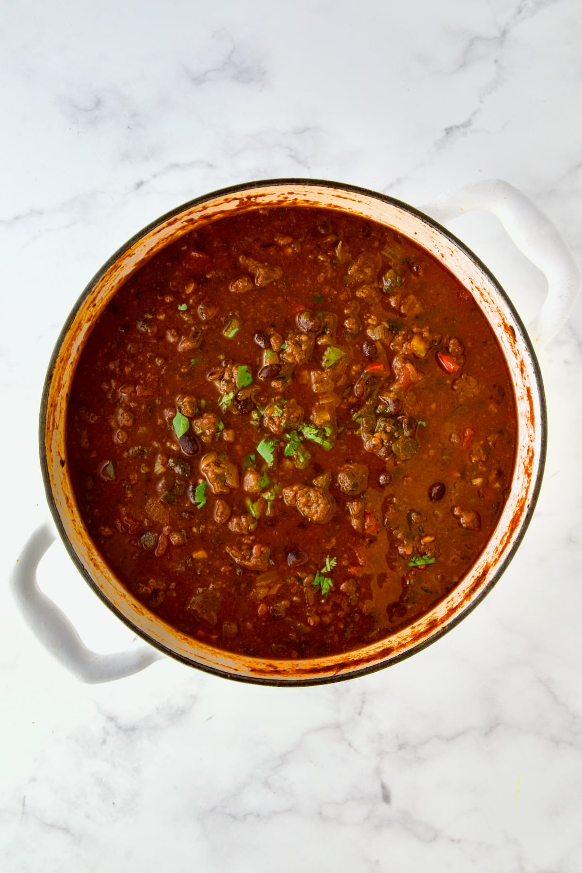 Finished chili in white enamel Dutch oven.