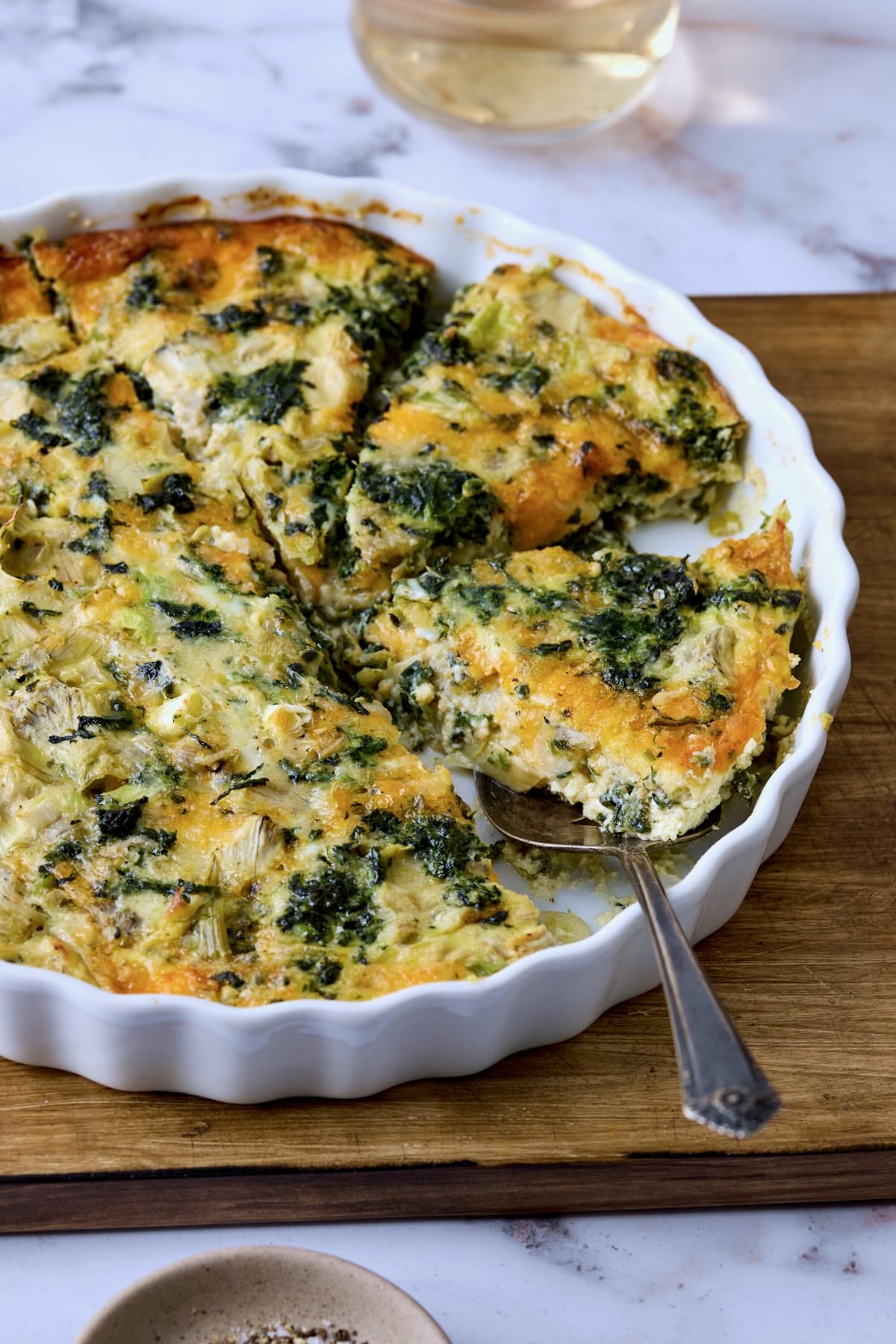 Crustless Spinach Artichoke Quiche with server lifting a piece from the quiche pan.