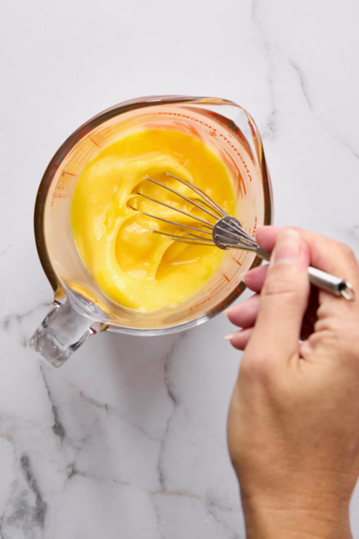 Eggs being blended in glass measuring pitcher.