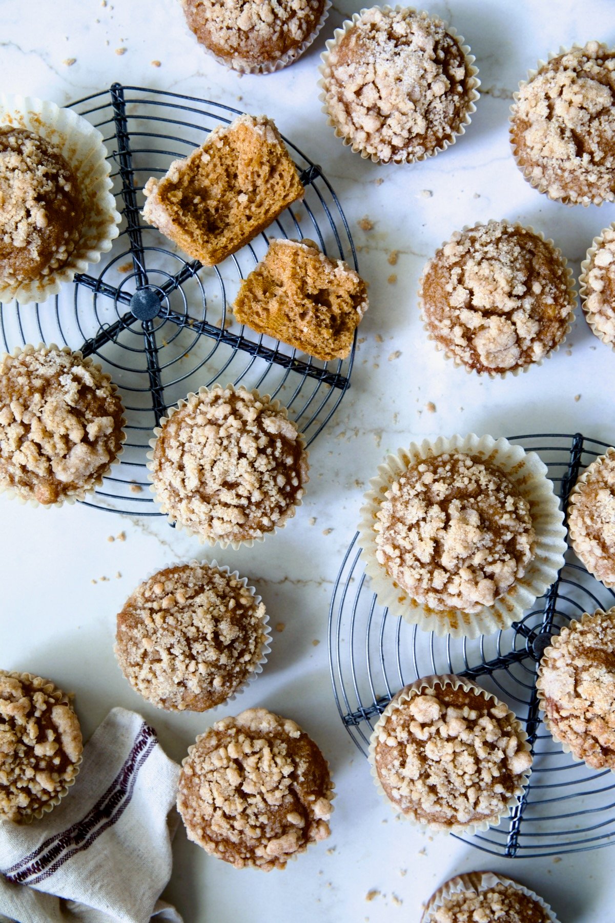 Pumpkin Streusel Muffins on two round cooling racks with one muffin cut in half.