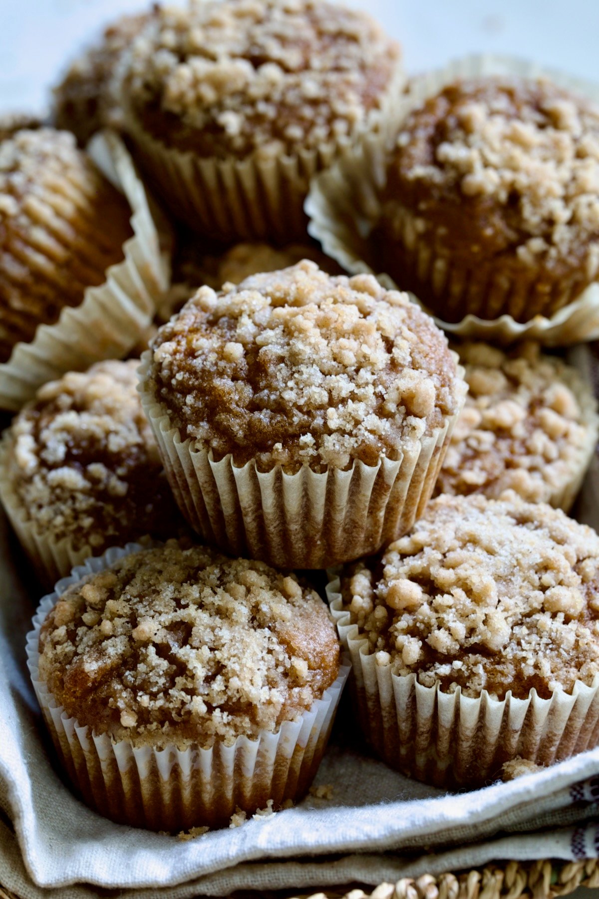 Stack of Pumpkin Streusel Muffins on napkin-lined basket.