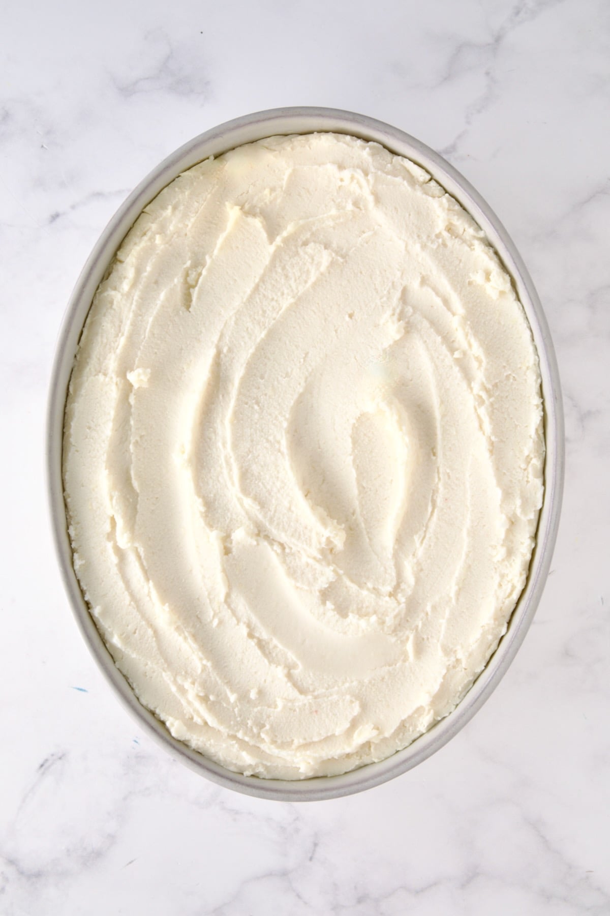 Unbaked mashed potatoes in oval baking dish.