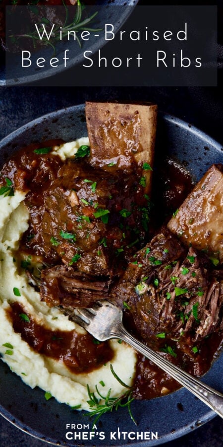 Pinterest graphic for Wine-Braised Beef Short Ribs showing them in a gray speckled bowl with fork over cauliflower puree.
