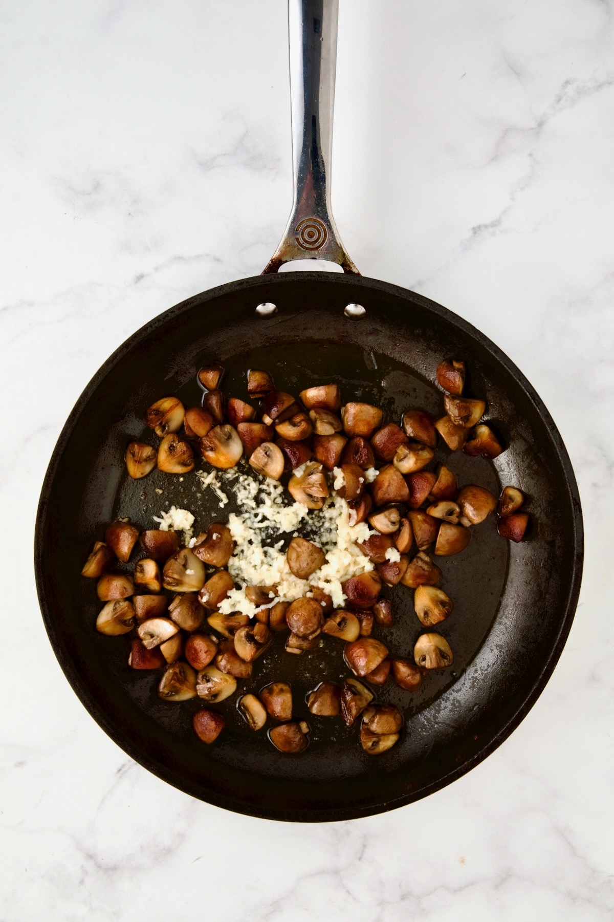 Browned cremini mushrooms in nonstick skillet with garlic added.
