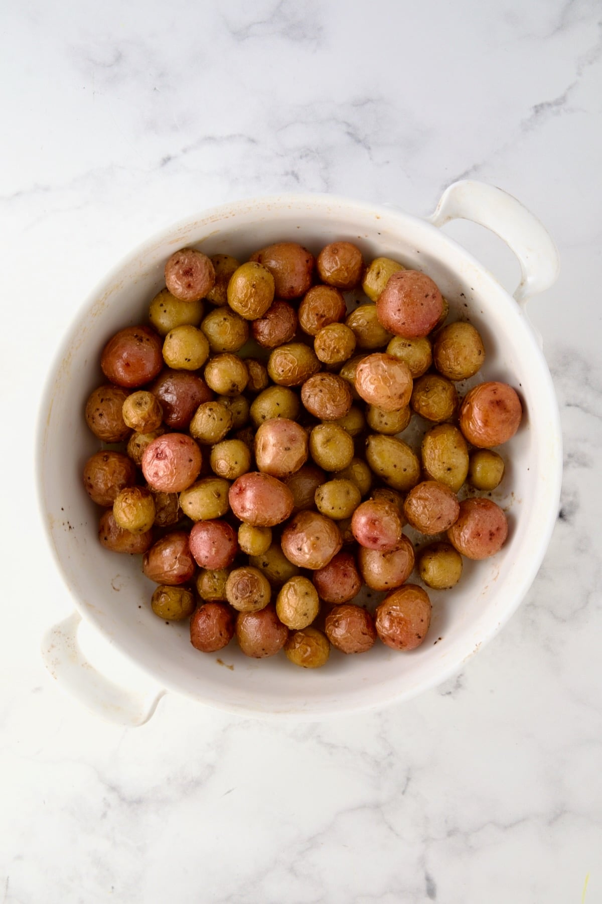 Roasted mini potatoes in round white baking dish.