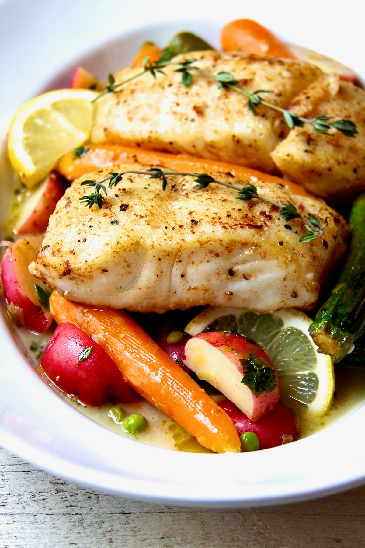 Two servings of Halibut with Braised Lemon Vegetables in white bowl.