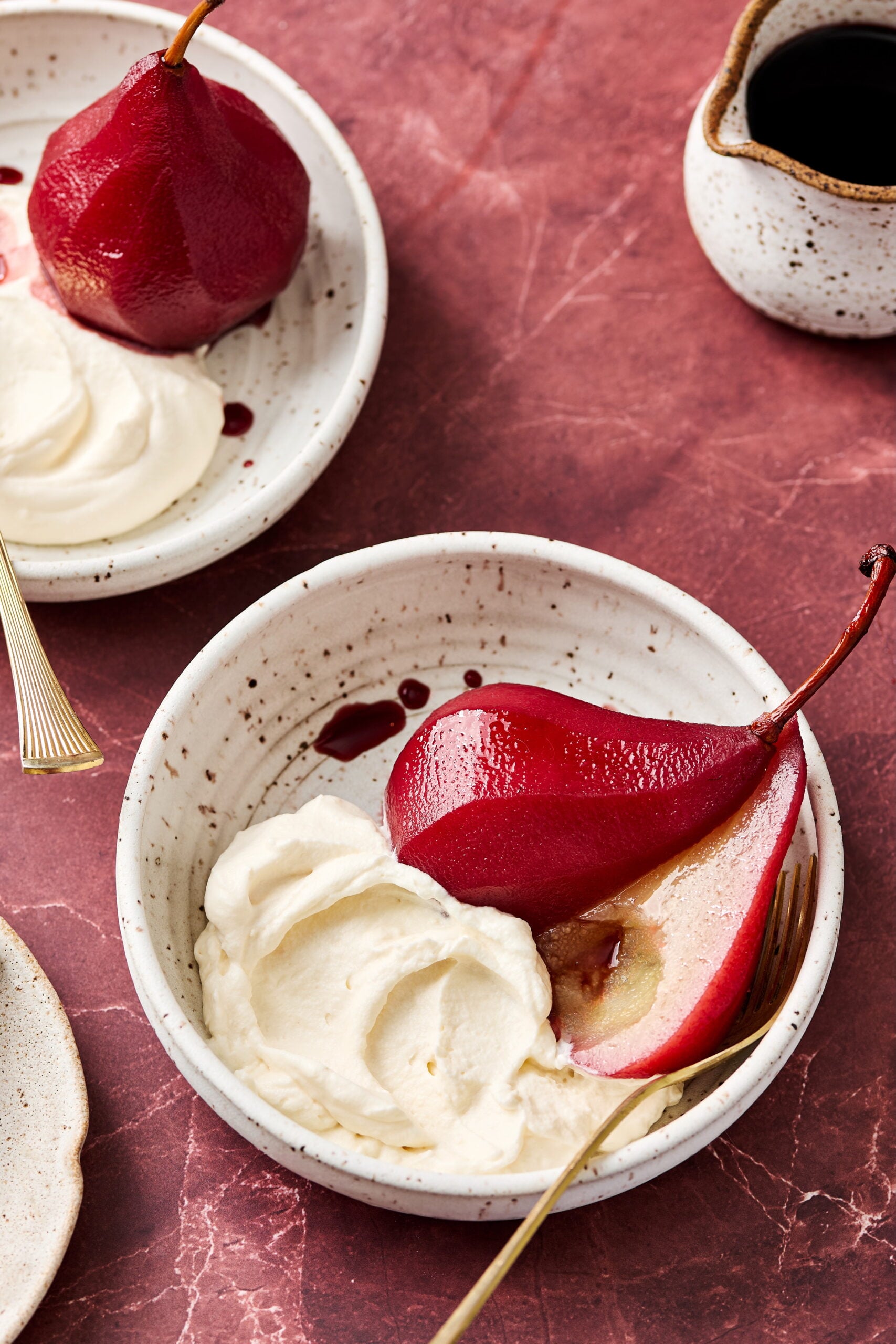 Poached pear sliced in half in a bowl with Mascarpone Whipped Cream.