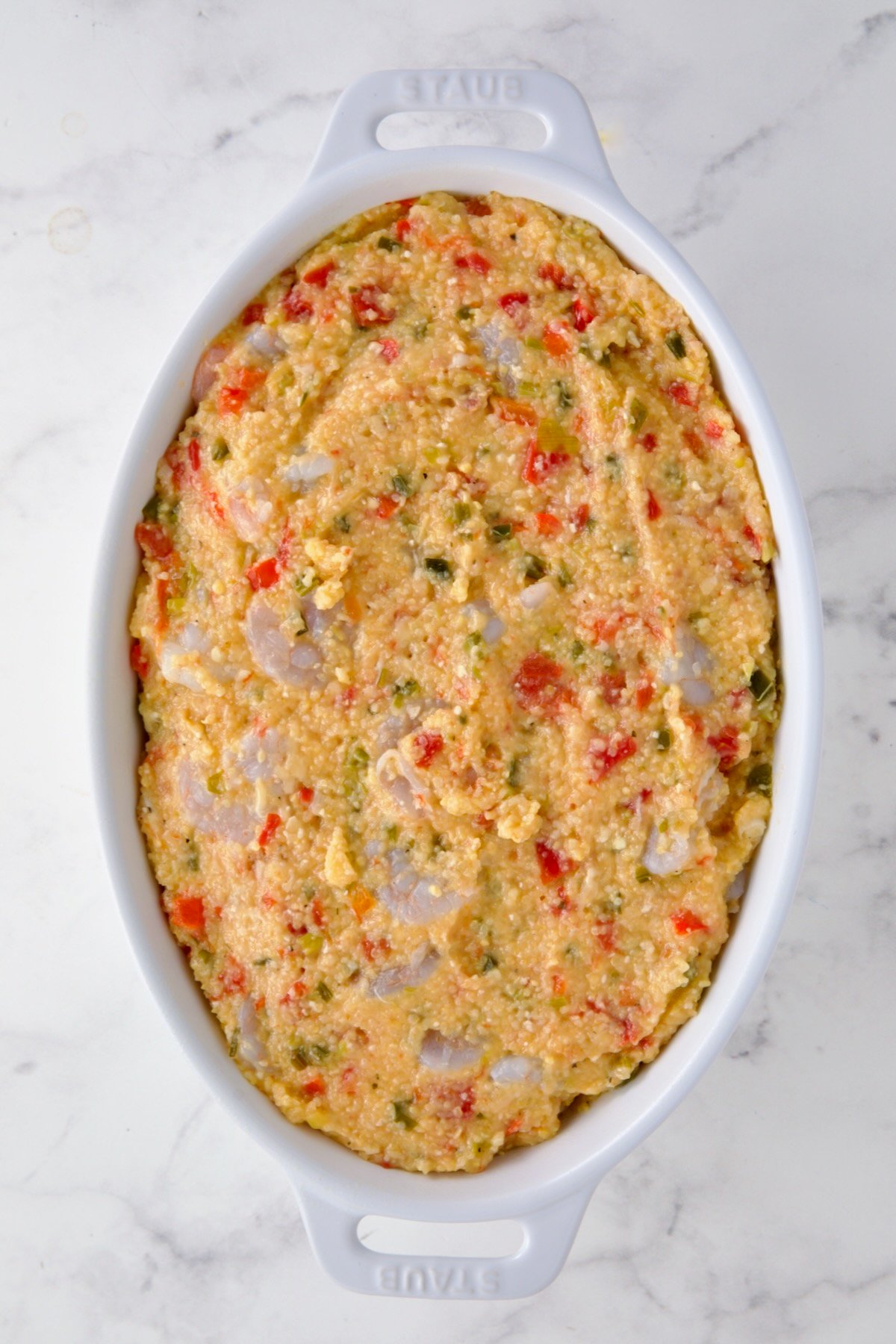 Shrimp and Grits Casserole in oval baking dish before the cheese is added.
