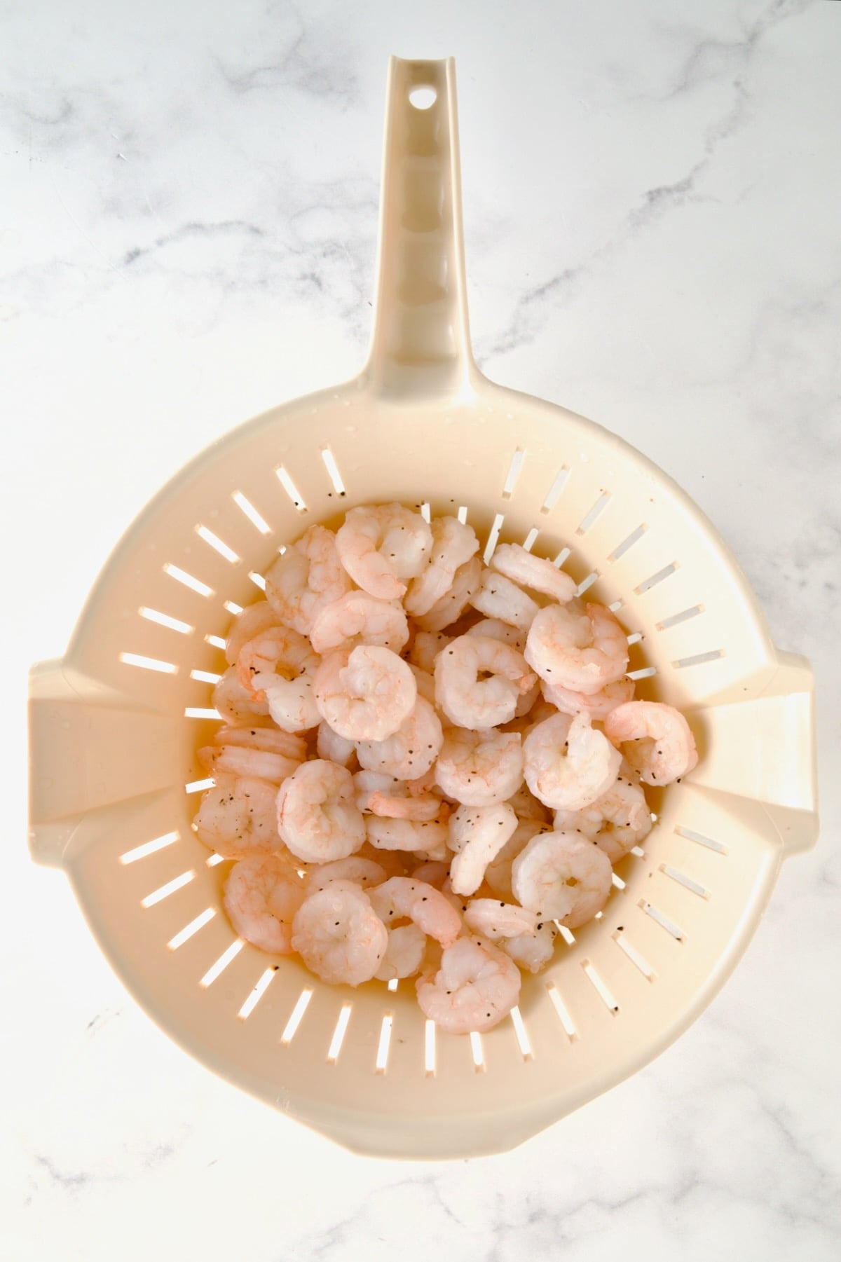 Cooked shrimp in plastic colander.