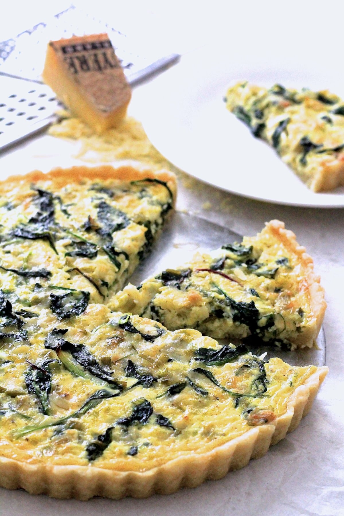 Greens, Leek and Gruyere Tart with two wedges cut out.