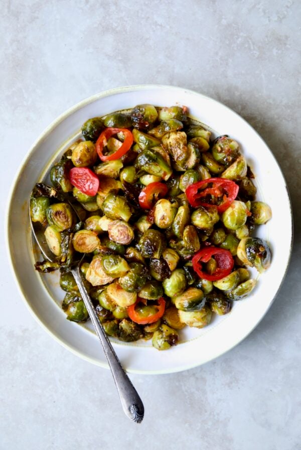 Hot Honey Brussels Sprouts in white serving bowl with serving spoon.