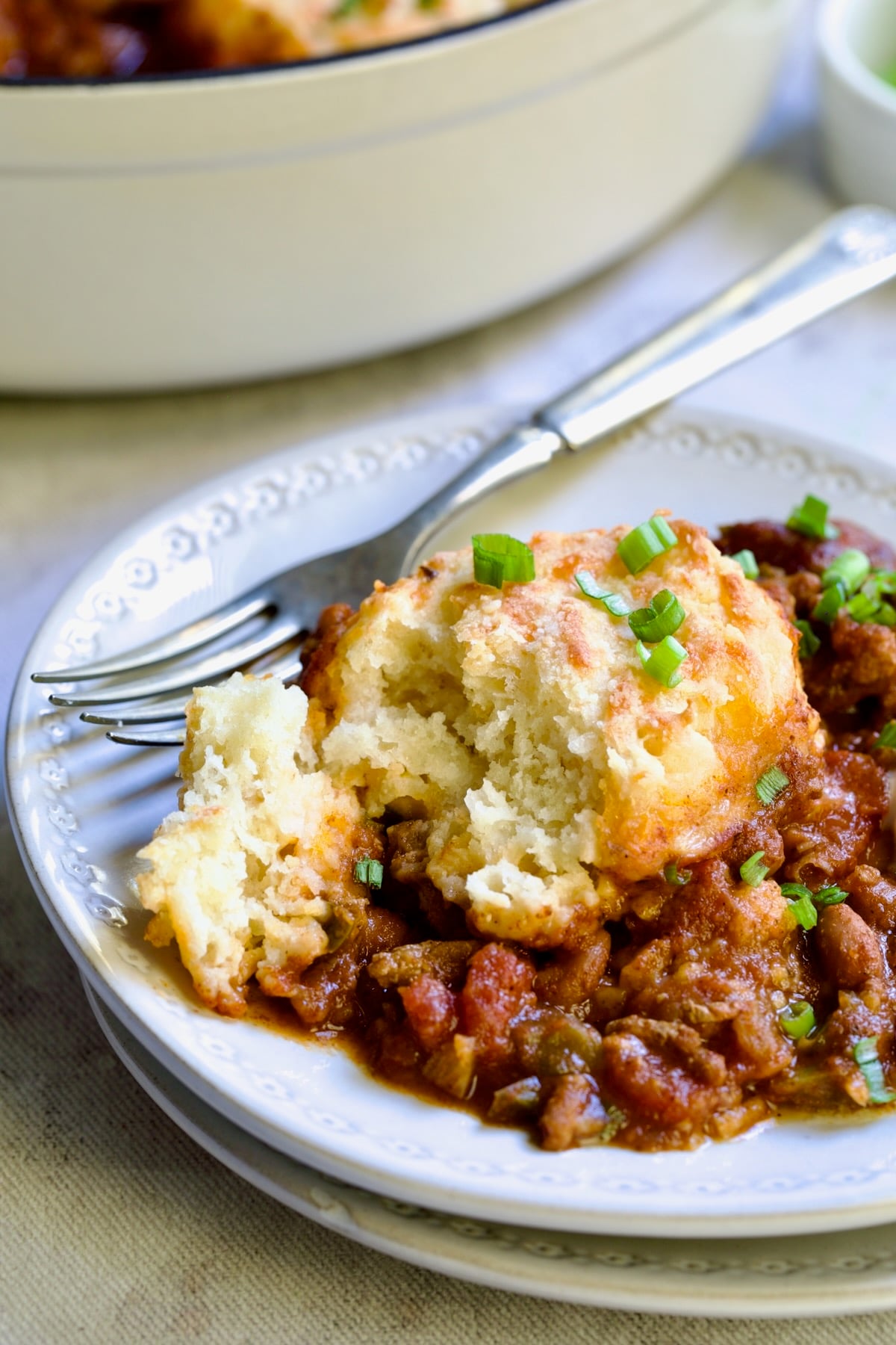 One serving of Biscuit-Topped Turkey Skillet Chili on small white plate with fork.
