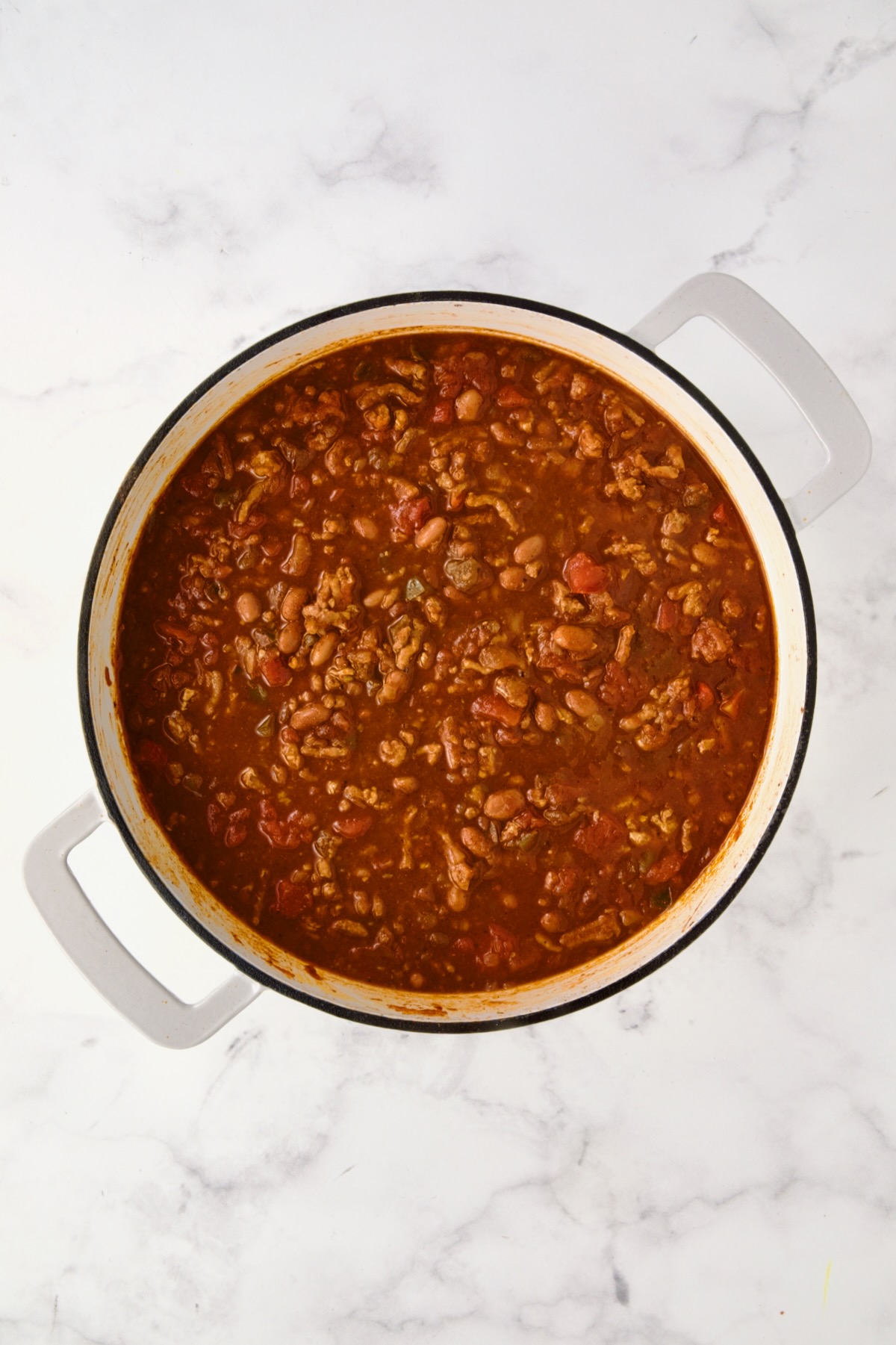 Cooked Turkey Skillet Chili in white enamel cast iron skillet read to be topped with biscuits.