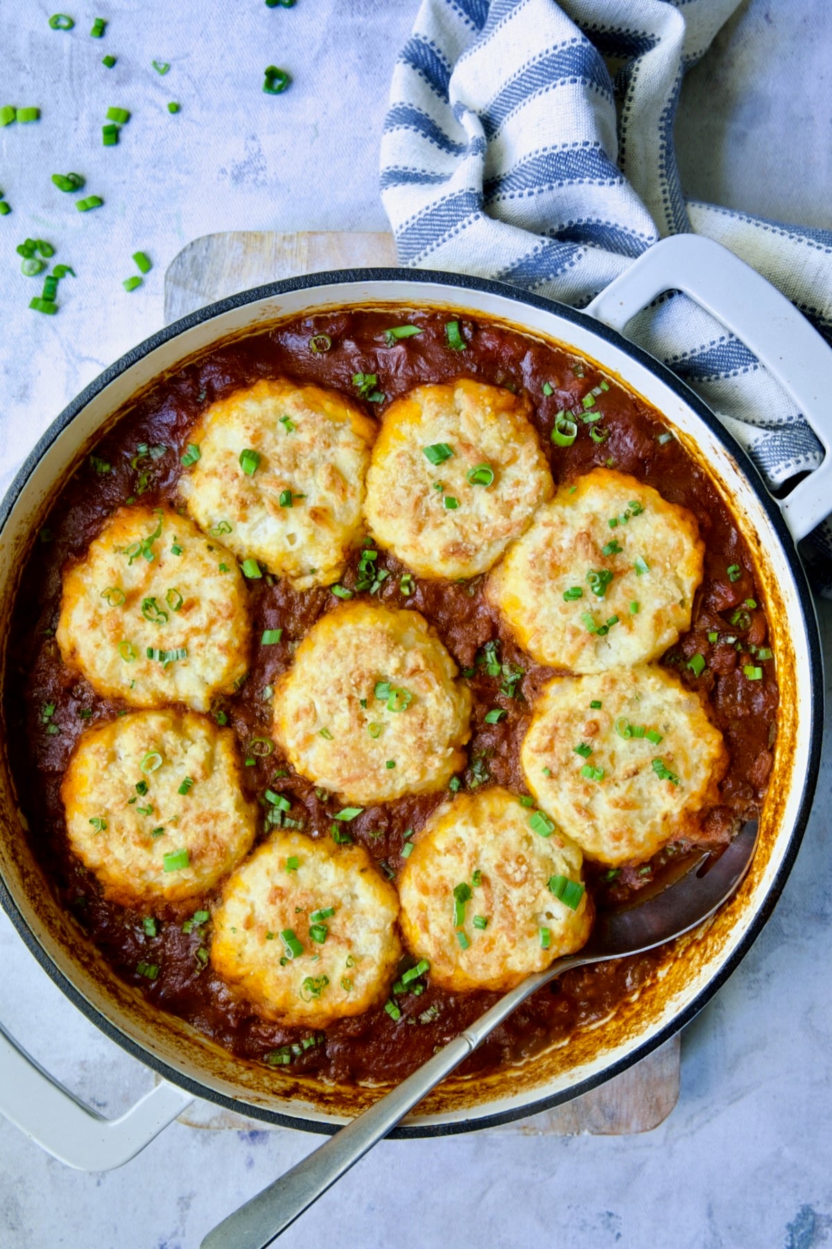 Biscuit-Topped Turkey Skillet Chili in white enamel cast iron skillet with stainless steel serving spoon.