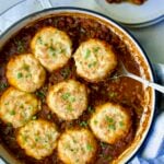Biscuit-Topped Turkey Skillet Chili in white enamel cast iron skillet with a piece removed onto a small plate.